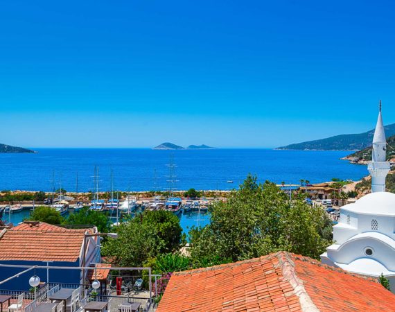 Scenic rooftop views over Kalkan harbour, Mouse Island, and the bay, with the village mosque and whitewashed houses in view