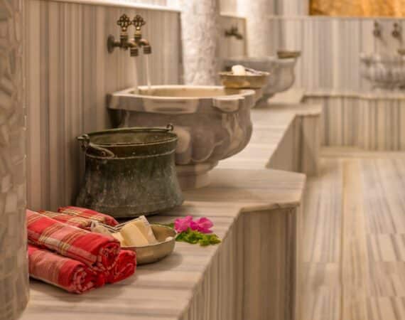 A marble hammam steam room in Kalkan with copper bowls and towels laid out for a Turkish bath ritual
