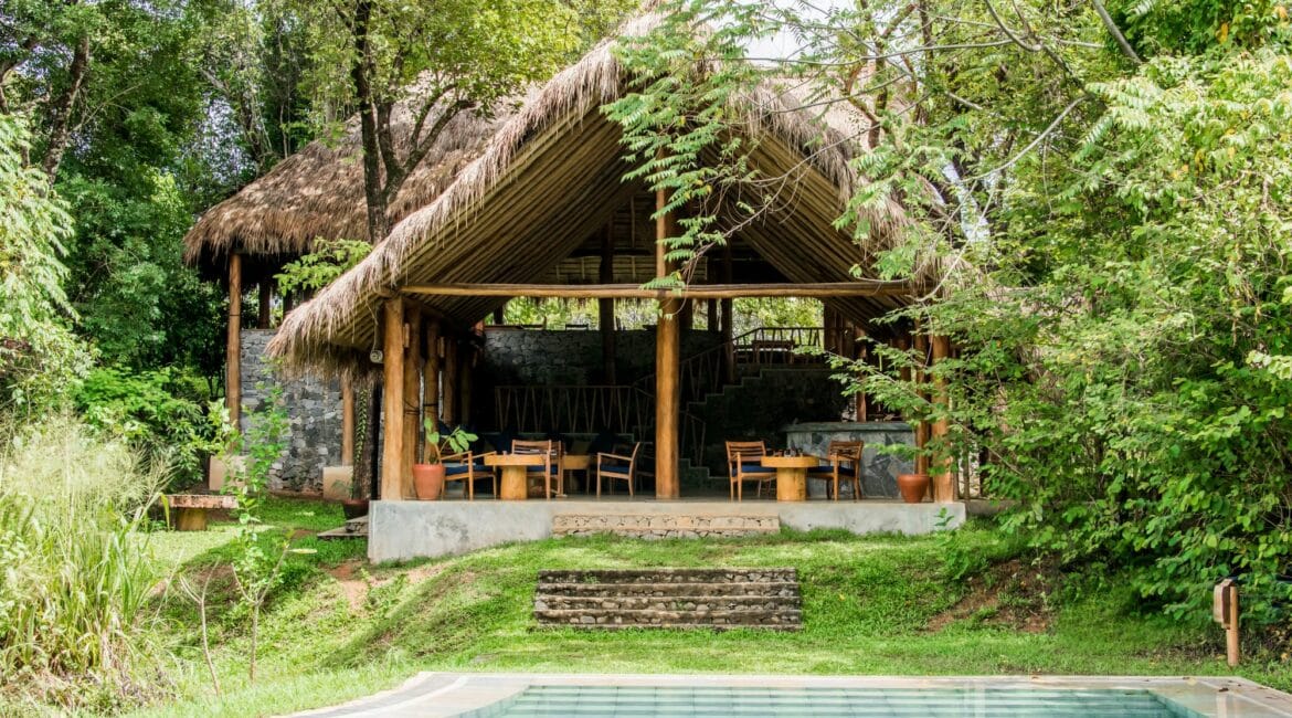Gal Oya Lodge main lodge by day, featuring open-air sitting area with natural wood furnishings and views over the surrounding forest in Gal Oya National Park, Sri Lanka.