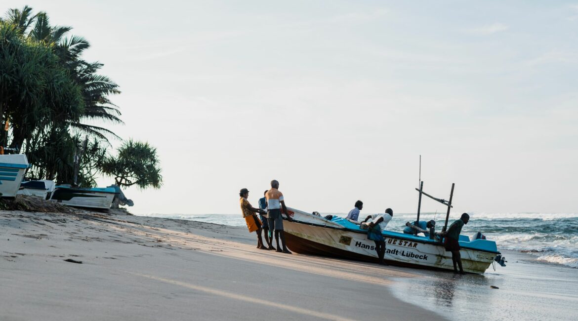 Vibrant fishing boats lined up on the sand at South Beach, Kathaluwa, with palm-fringed shores and the Indian Ocean shimmering beyond.