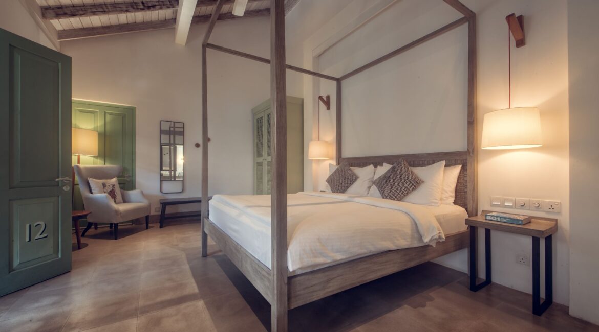Bazaar Bedroom at Fort Bazaar Hotel Sri Lanka with modern, comfortable interiors in neutral tones, featuring a king-size bed with white linens, minimalist furnishings, and soft ambient lighting.