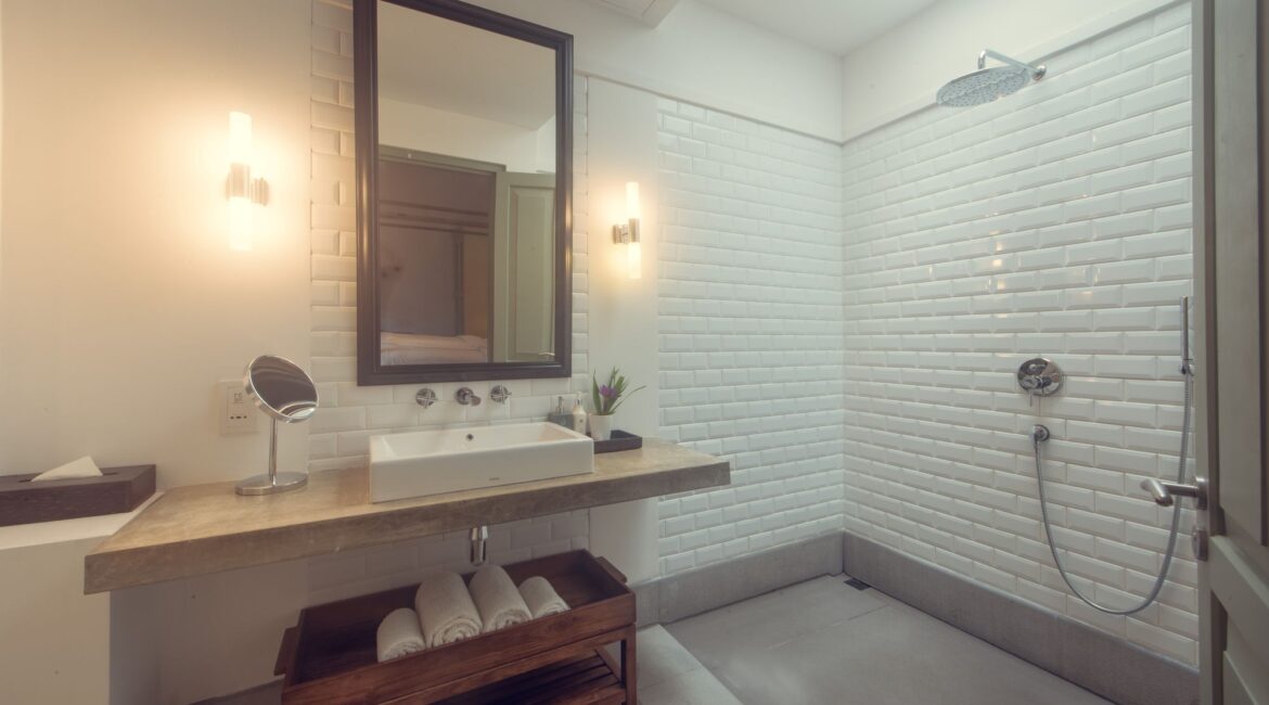 Modern en suite bathroom in the Bazaar Bedroom at Fort Bazaar Hotel Sri Lanka, featuring a rainfall shower with glass partition, contemporary fittings, and a sleek WC.