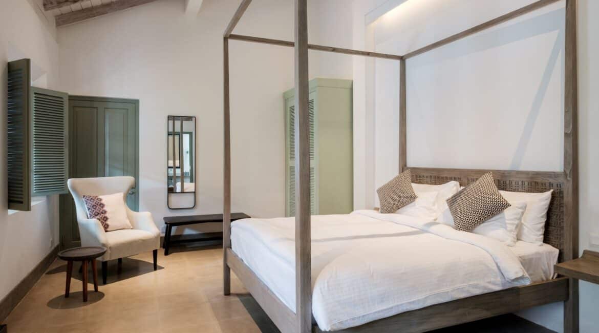 azaar Bedroom at Fort Bazaar Hotel Sri Lanka adorned in stylish neutral tones, with a king-size bed dressed in white linens, minimalist wooden furnishings, and soft ambient lighting.