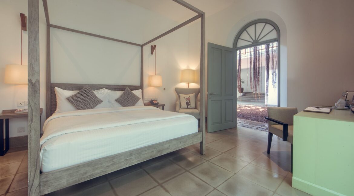 anyan Bedroom at Fort Bazaar Hotel Sri Lanka featuring a modern interior with minimalist décor, a king-size bed dressed in white linens, and contemporary furnishings.