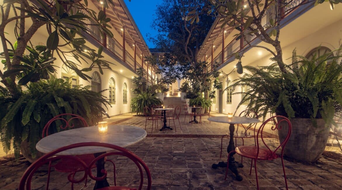 Furnished courtyard at Fort Bazaar Hotel Sri Lanka illuminated at night, featuring comfortable seating, lanterns, and lush greenery creating a warm, inviting atmosphere.