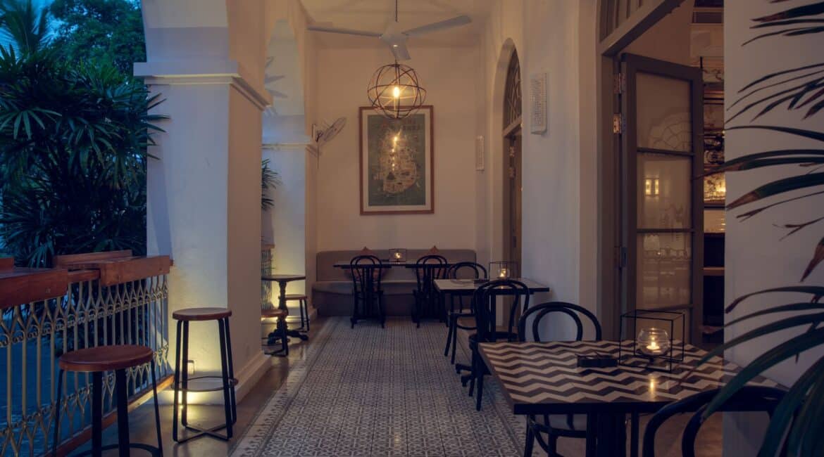 Church Street Social veranda at Fort Bazaar Hotel Sri Lanka with stylish seating and abundant foliage spilling in, creating a relaxed, airy setting.