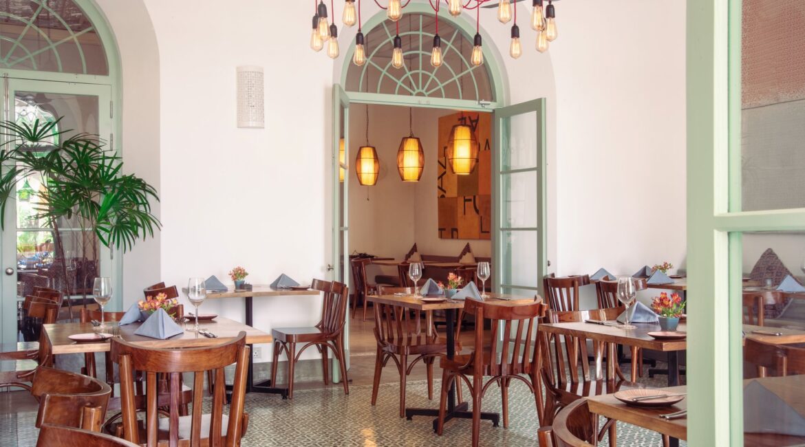Church Street Social Restaurant at Fort Bazaar Hotel Sri Lanka dressed for lunch or dinner, featuring high ceilings, pastel-coloured walls, dark wooden tables set with glassware, and elegant lighting.