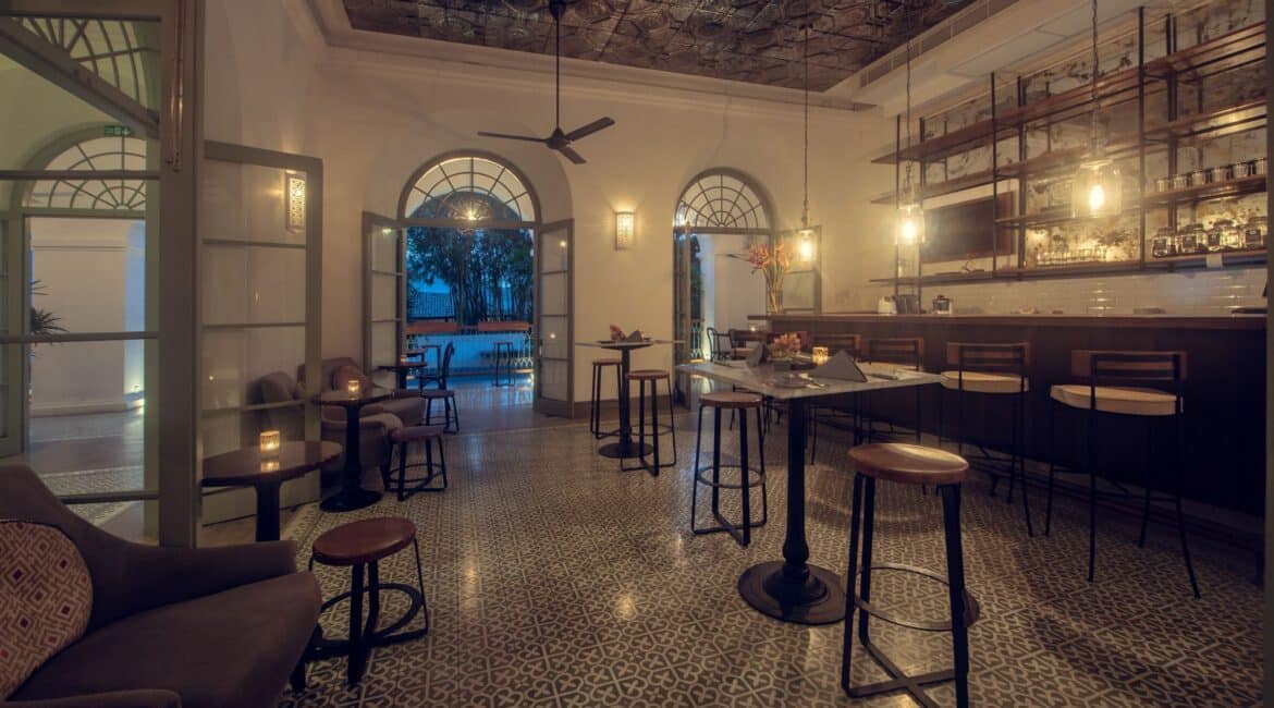 Church Street Social Bar at Fort Bazaar Hotel Sri Lanka with a sleek counter, bar stools, stylish shelving displaying bottles, and warm ambient lighting.