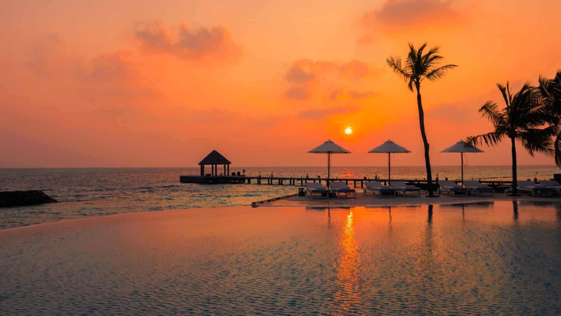 Komandoo Island Resort & Spa striking hot orange sunset palm fringe sea views and swimming pool