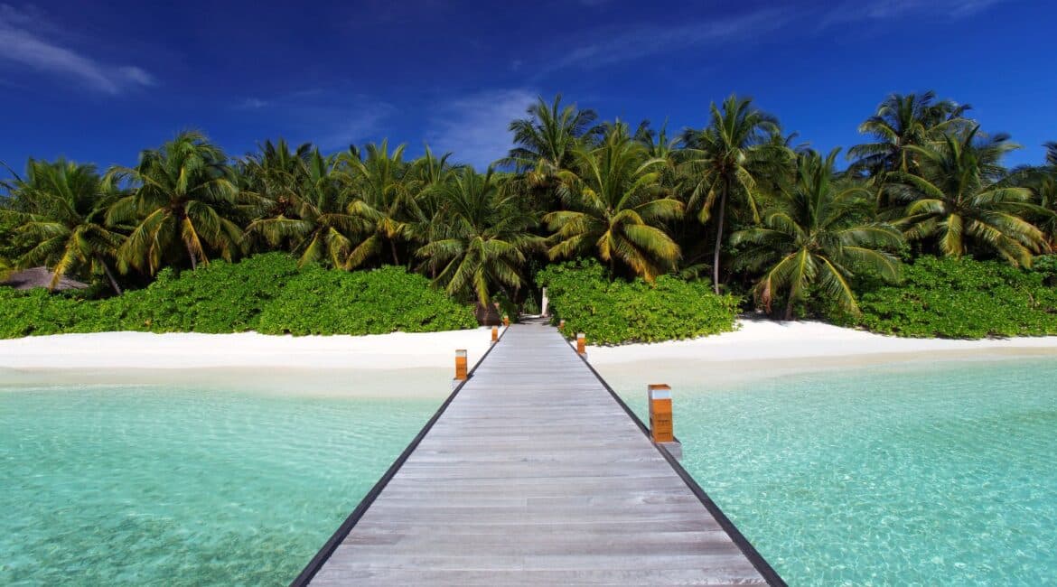 Baros jetty from the white sand and palm fringed shores over the crystal clear Indian Ocean