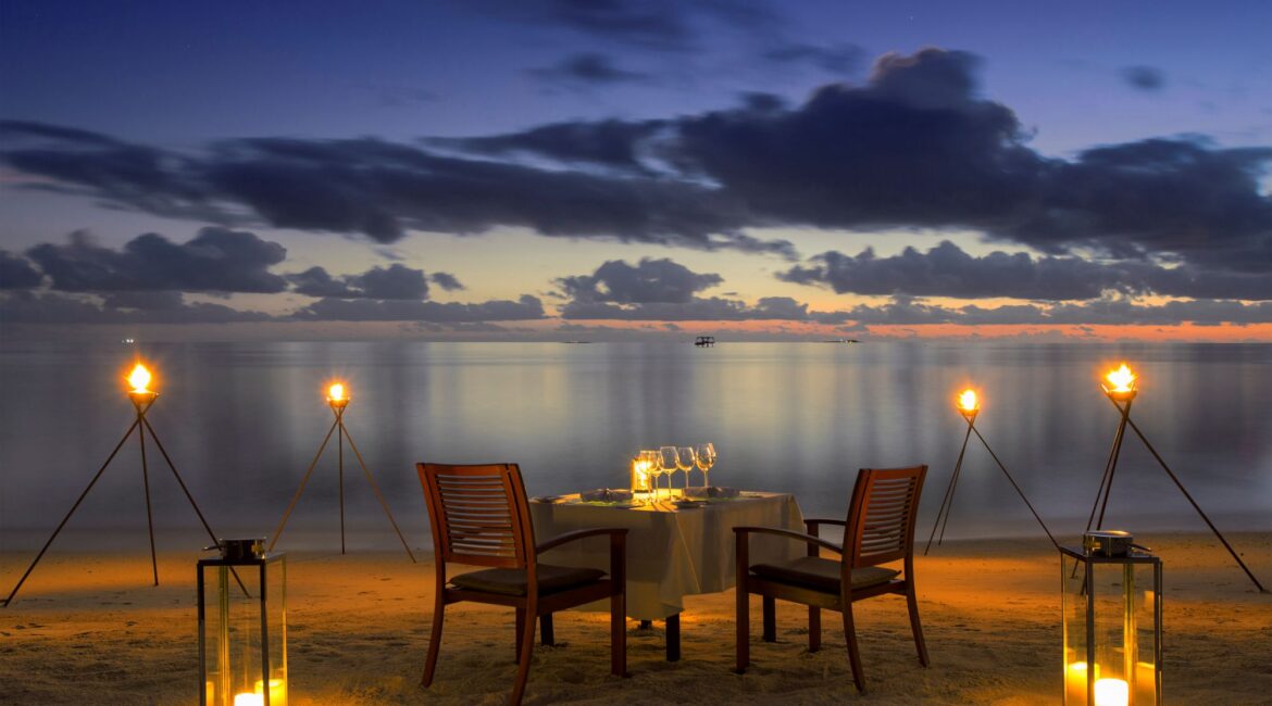 twilight beach dinner at Baros Maldives lit by candles against the ocean backdrop