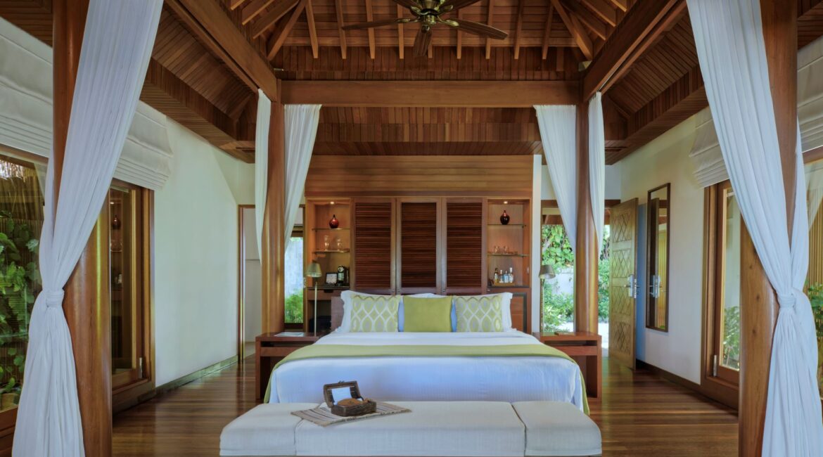Baros Pool Villa beautifully appointed interiors spacious double bedroom and dark wood with flowing linen Baros Maldives