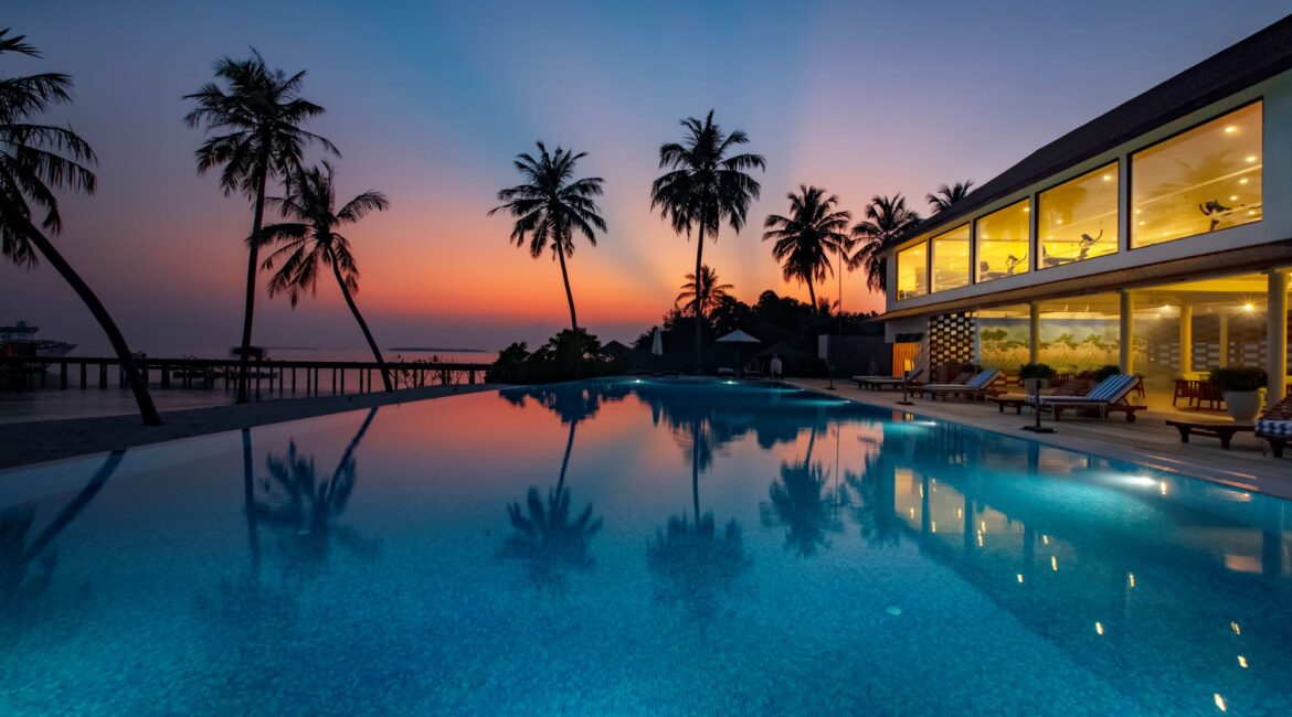 Reethi Faru Resort swimming pool at sunset in the Maldives