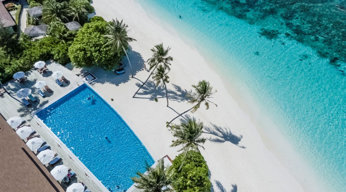 Reethi Faru Resort the swimming pool and turquoise sea shimmering from above Maldives