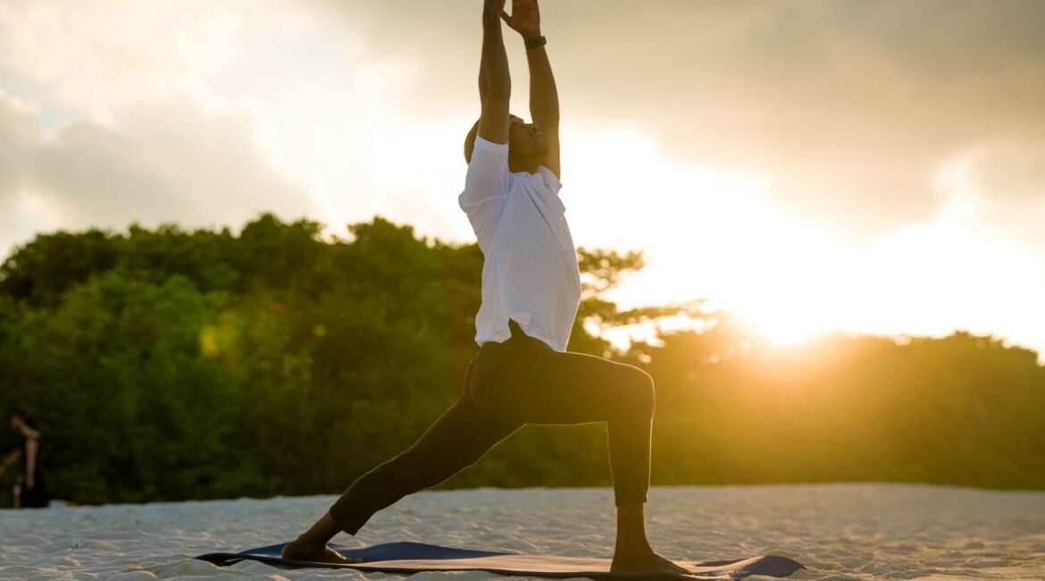 Yoga at sunset on the beach Reethi Faru Resort in the Maldives