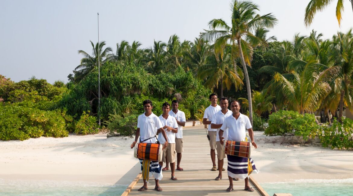 Reethi Faru Resort team welcoming guests on arrival in a traditional Maldivian way