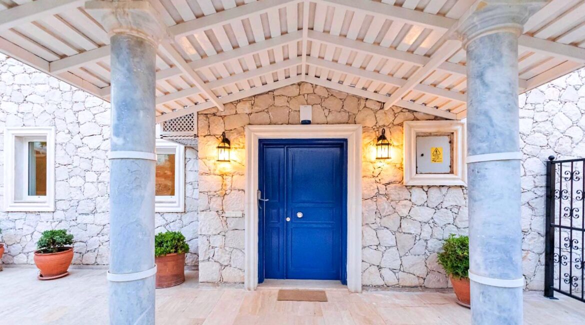 Covered entrance terrace at Villa Bahce Kalkan with stone pillars and blue front door
