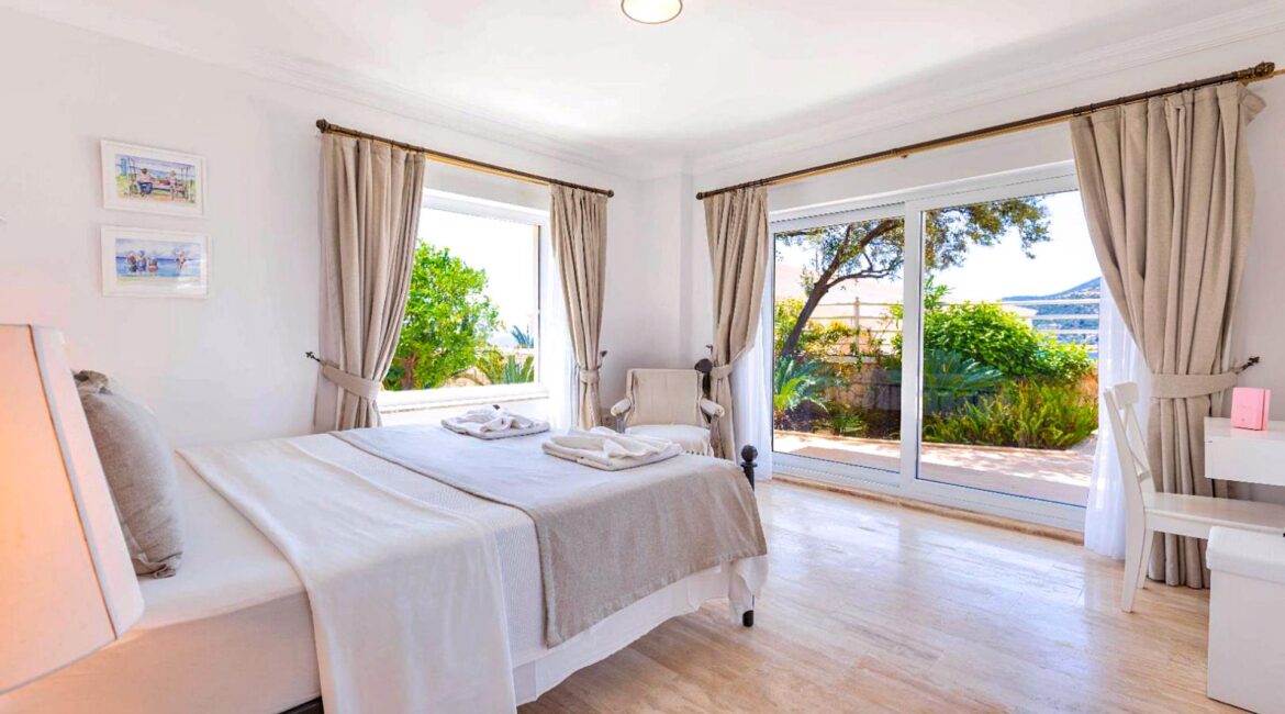 Bright double bedroom at Villa Bahce Kalkan with large glass doors opening to the terrace