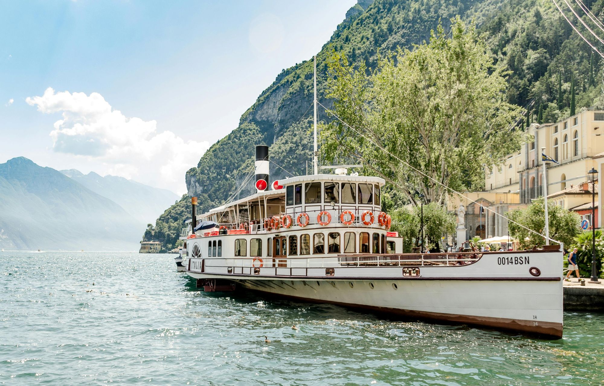 Traditional ferry boat travelling across Lake Garda with dramatic mountain scenery in northern Italy