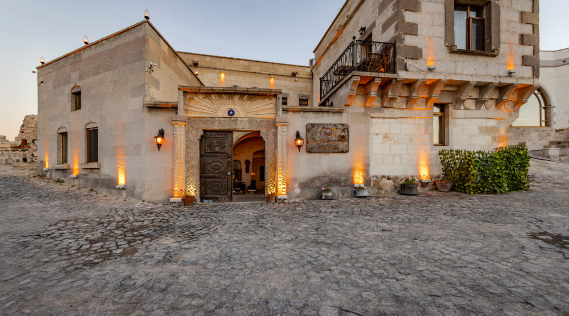 Exterior entrance of Eyes of Cappadocia with traditional stone architecture at dusk