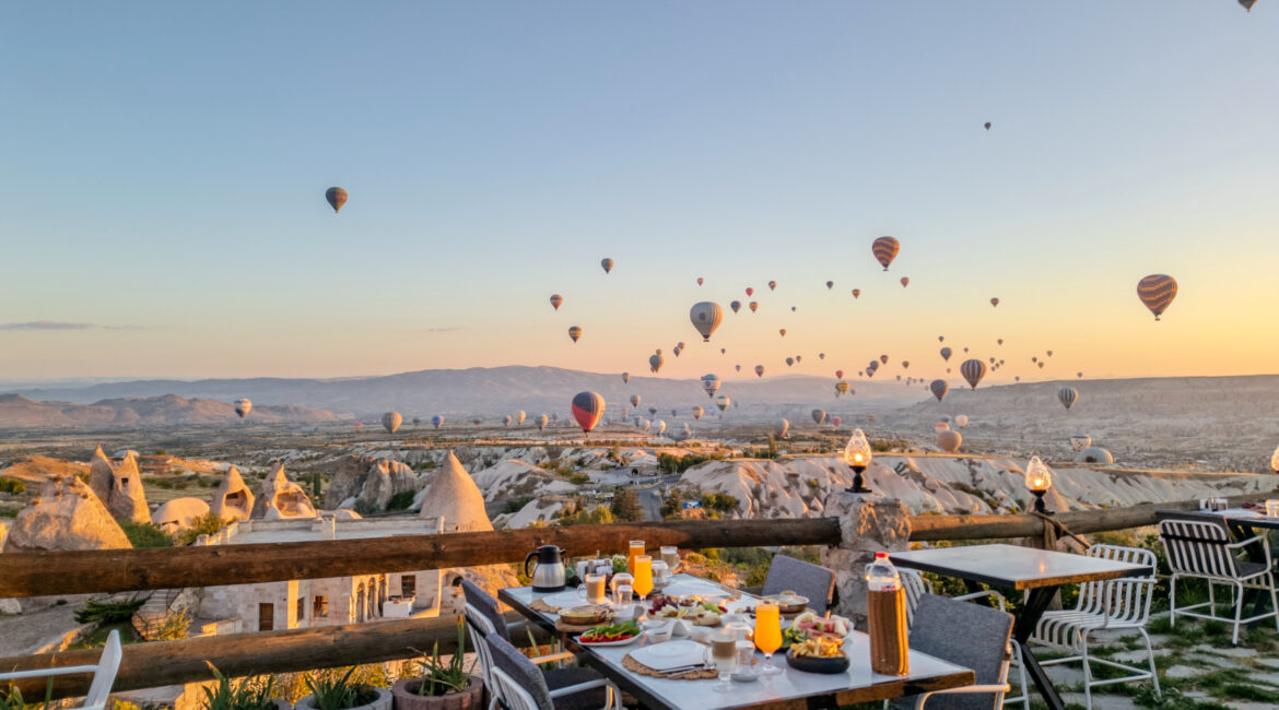 Breakfast terrace at Eyes of Cappadocia with hot air balloons rising over Uchisar