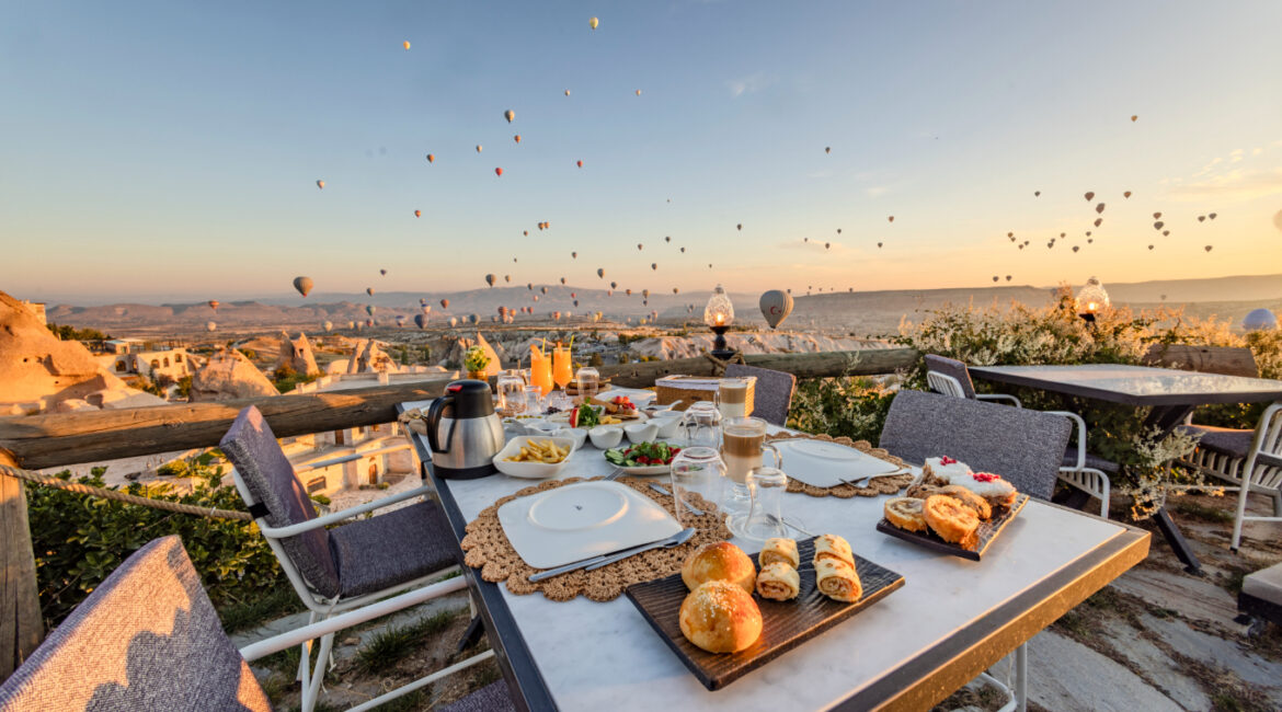 Breakfast terrace in Uchisar with hot air balloons drifting across the Cappadocia skyline