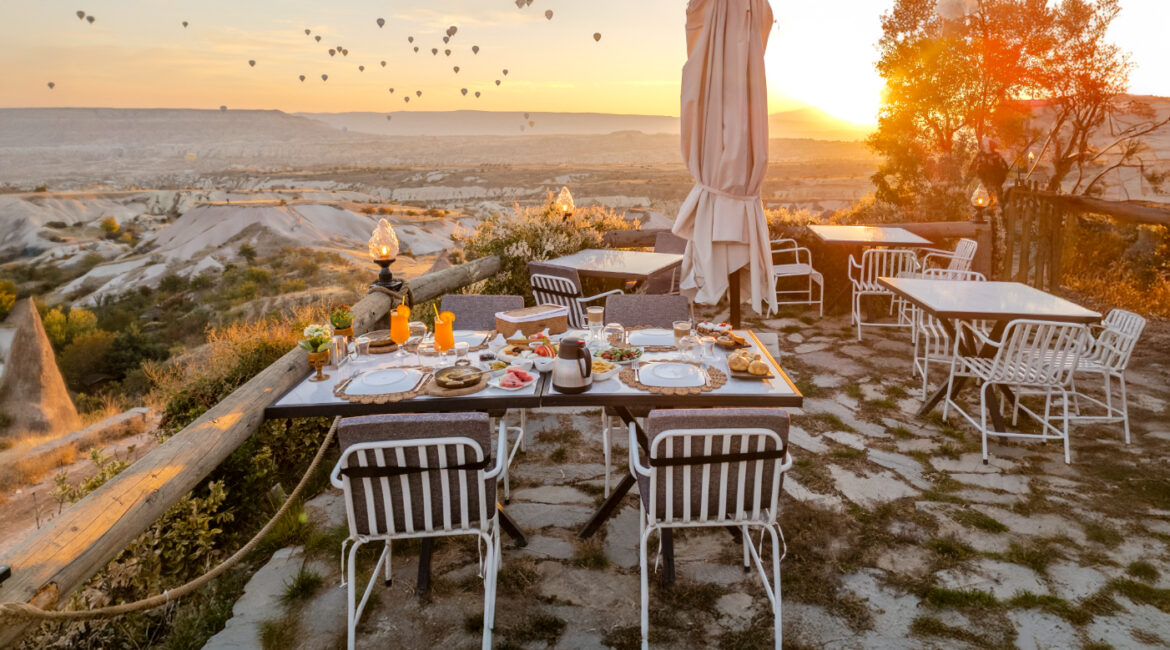 Sunrise terrace at Eyes of Cappadocia overlooking Uçhisar with hot air balloons in the distance