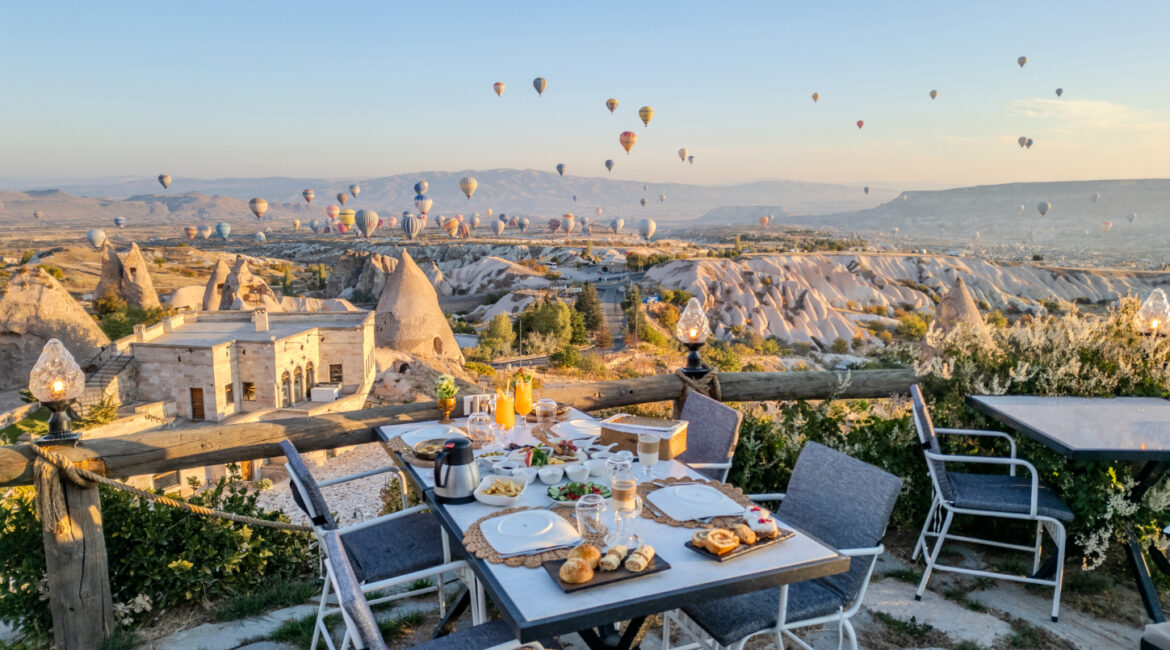 Terrace dining at Eyes of Cappadocia with panoramic views across Uçhisar and balloon-filled skies