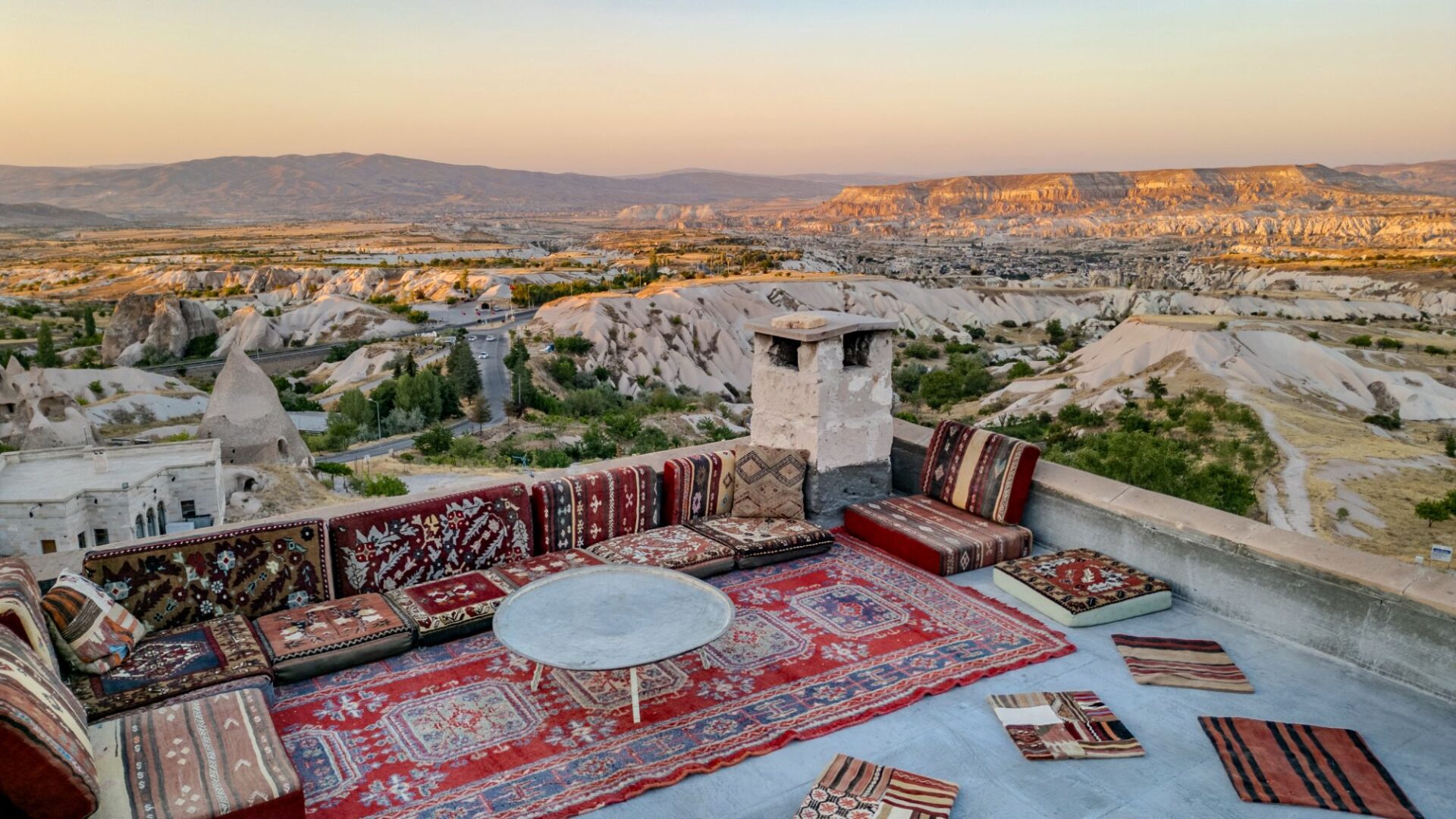 Rooftop kosk seating area with sweeping views across Cappadocia at sunset
