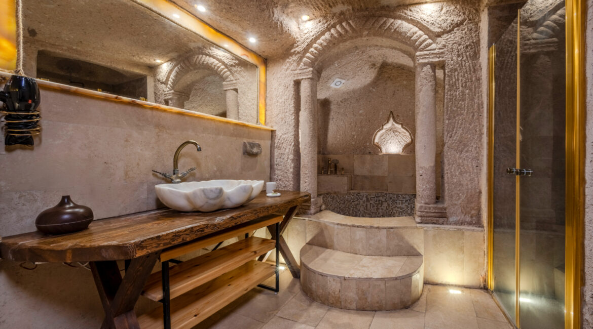 Cave bathroom with walk-in shower and natural stone finishes in Görkemli Suite