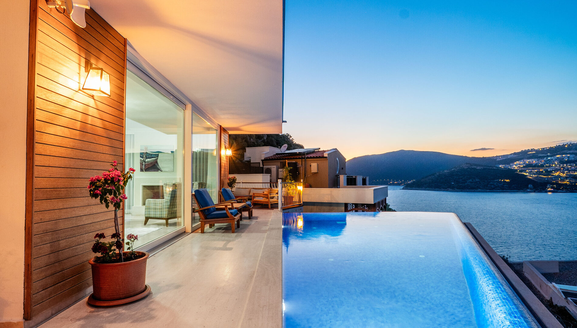 Infinity pool at Villa Cennet Koy Kalkan at dusk with illuminated terrace and views across Kalkan Bay and harbour