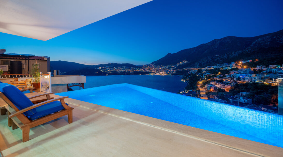Infinity pool at Villa Cennet Koy Kalkan at night with panoramic views over Kalkan Bay and illuminated harbour