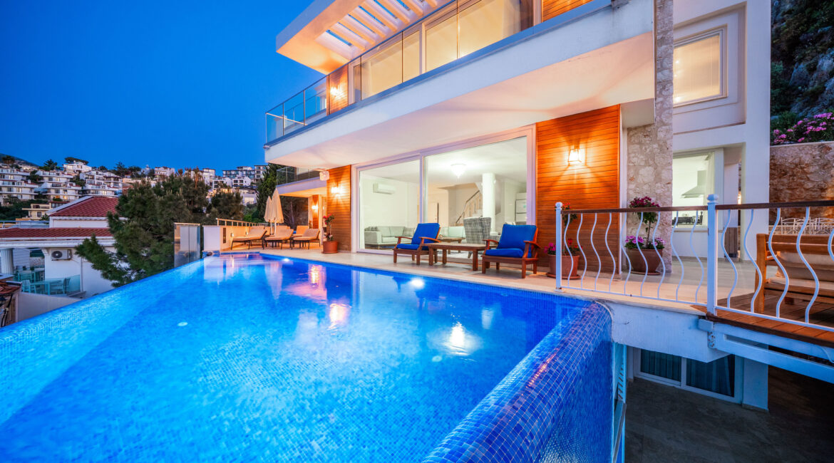 Villa Cennet Koy Kalkan exterior at dusk with infinity pool, terrace seating and illuminated modern architecture