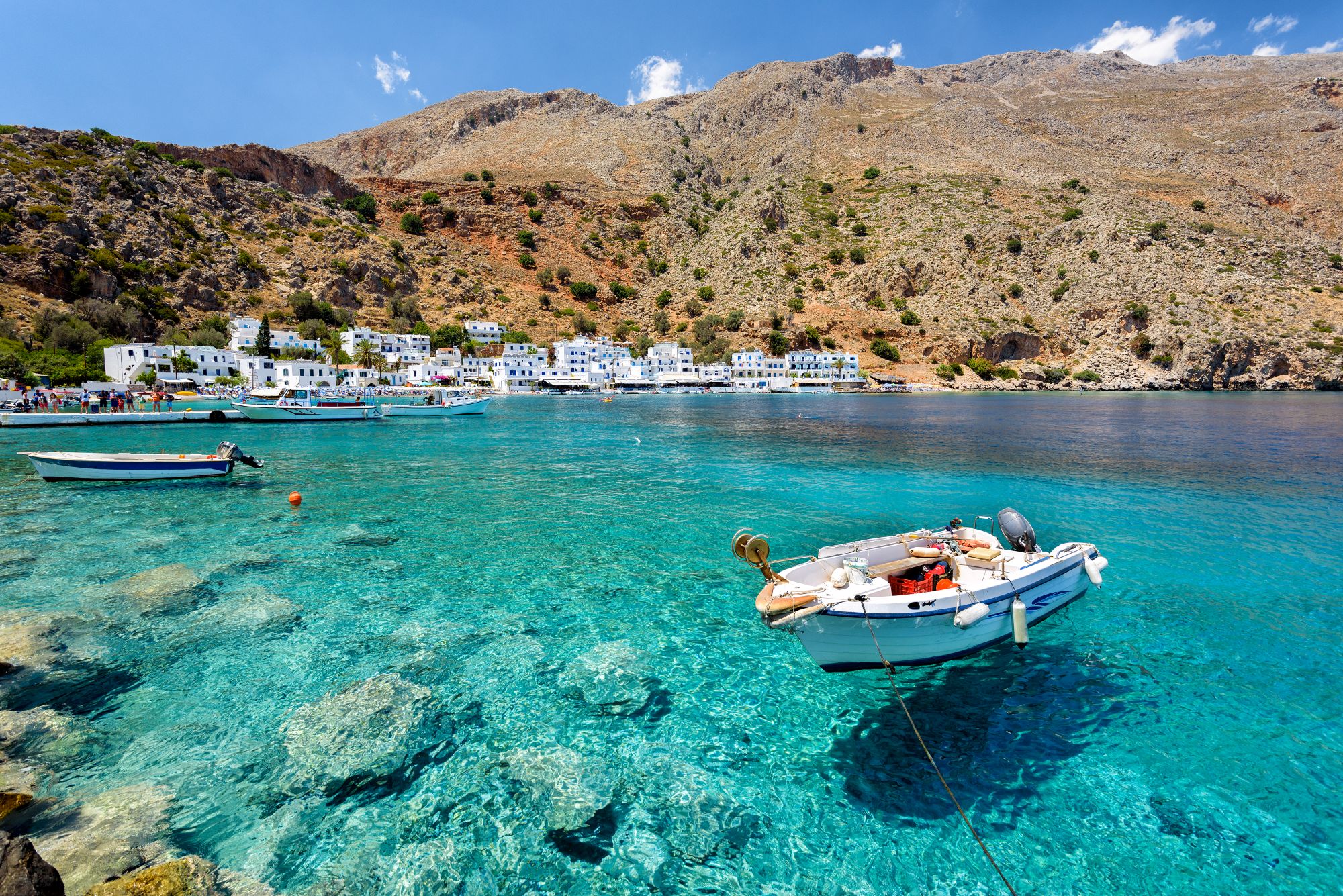 Small boat in a secluded bay with crystal-clear turquoise water in Crete