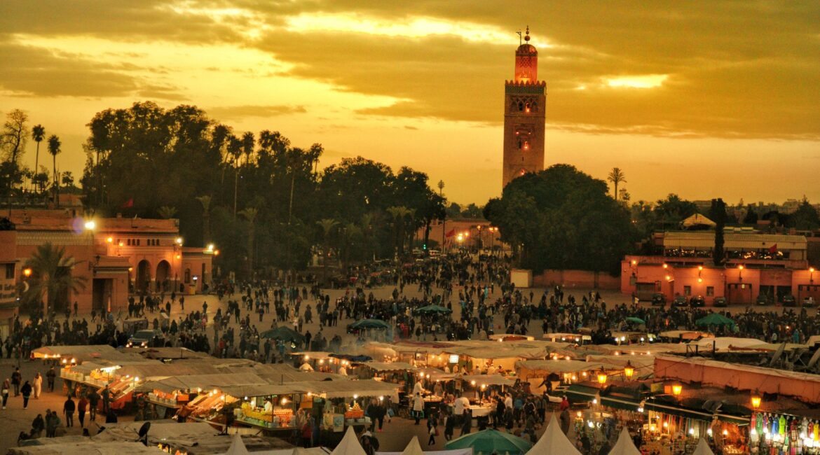 Sunset over Jemaa el-Fnaa square with mosque and market stalls in Marrakech
