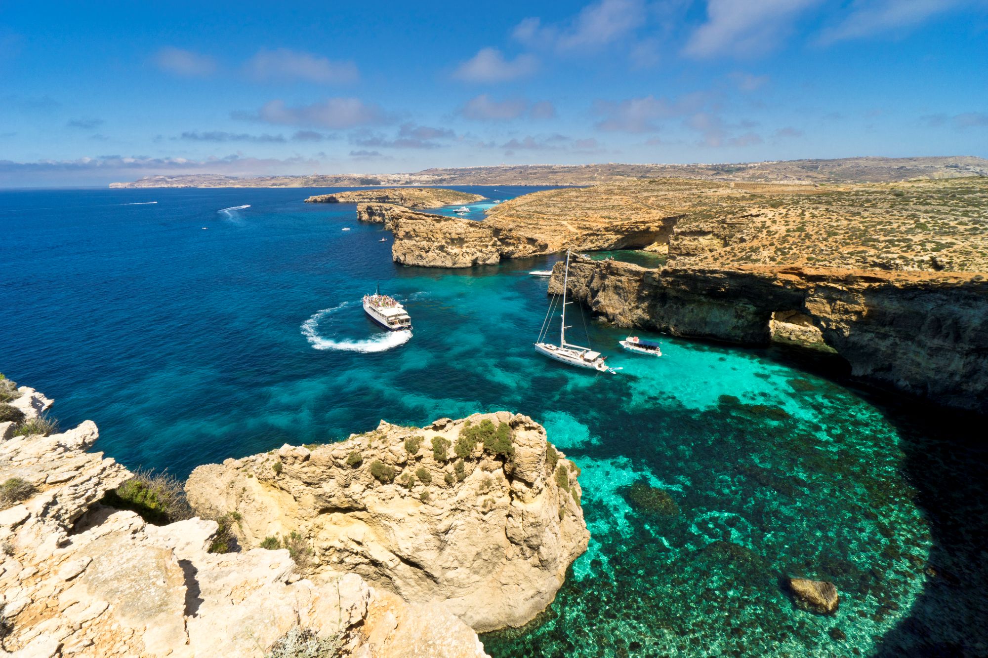 View over Gozo’s coastline with cliffs and clear blue bay below