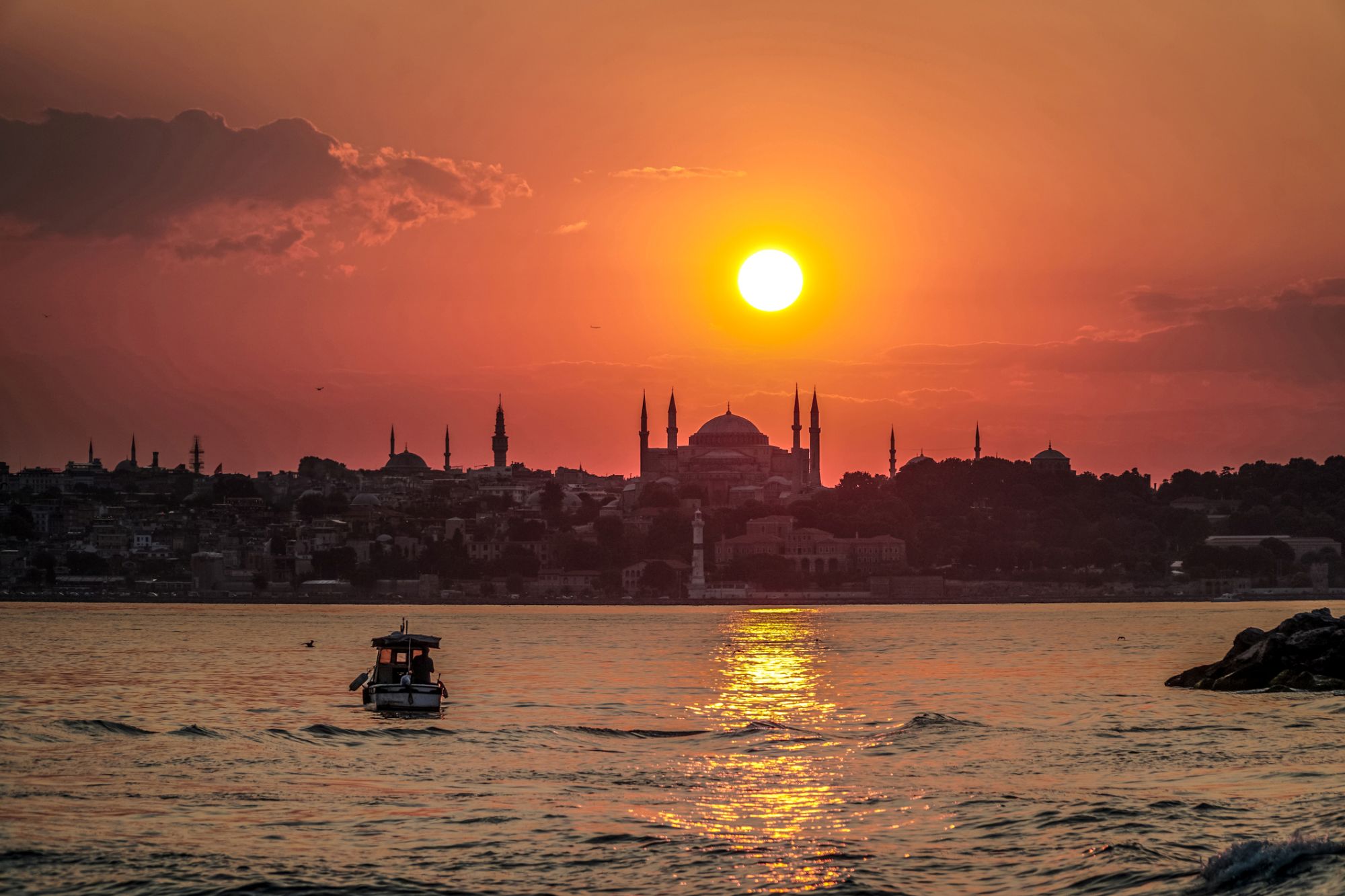 Golden sunset over the Bosphorus in Istanbul with Ortakoy waterfront and ferries crossing between Europe and Asia