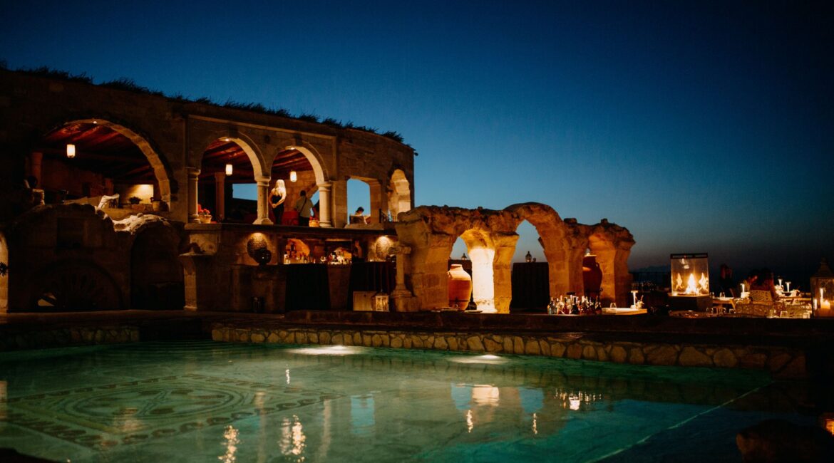 Heated outdoor pool and historic stone terraces at Museum Hotel Cappadocia at dusk