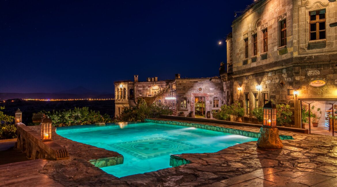 Heated outdoor pool at Museum Hotel Cappadocia overlooking Cappadocia at night