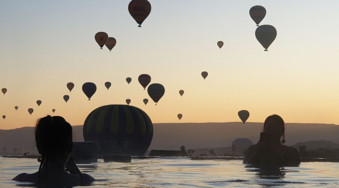 Hot-air balloons rising above the pool at Museum Hotel Cappadocia