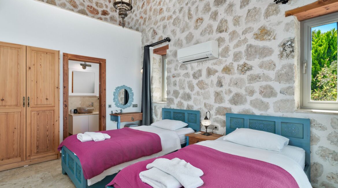 Twin bedroom with traditional stone walls at Villa Sedir Ev
