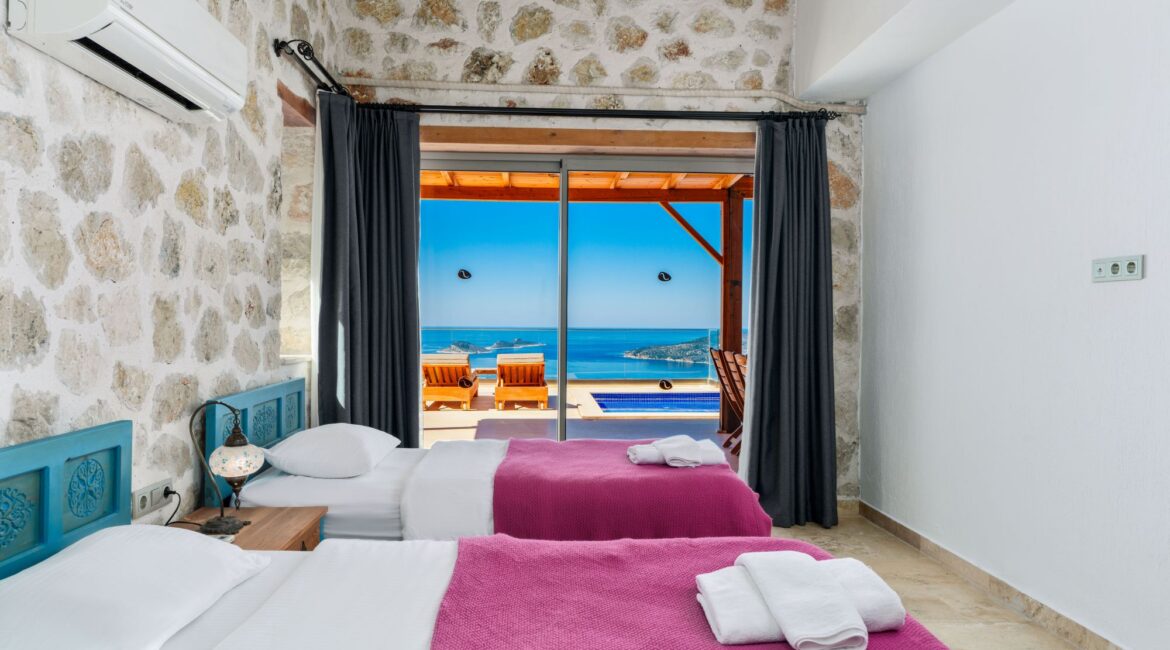 Twin bedroom with traditional stone walls at Villa Sedir Ev